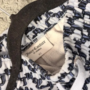 Juicy Couture mönstrade mjukisbyxor XS - Säljer ett par vita mjukisbyxor från Juicy Couture med svart mönster över hela byxan. Byxorna har resår i midjan, vita dragsnören och dragkedjefickor. Perfekta för en chill och trendig look.