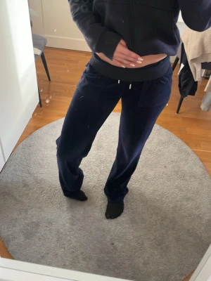 Mörkblå mjukisbyxor ifrån juciy couture - Mörkblå mjukisbyxor ifrån juciy couture. Byxorna har fickor fram och bak med silvriga detaljer på bakfickorna. Perfekta för en chill och avslappnad stil.