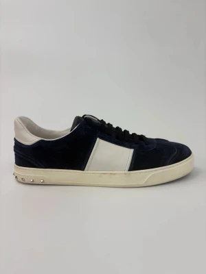 Valentino flycrew skor - Snygga mörkblå sneakers från Valentino med vit panel på sidan, vita detaljer vid hälen och svart snörning. Skorna har en krämfärgad sula och små silverfärgade nitar baktill. Ovandelen är i mocka och läder för en lyxig känsla.