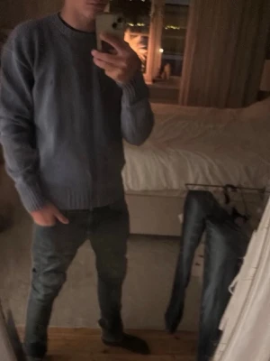 Blå stickad tröja från Polo Ralph Lauren - Säljer en stilren blå stickad tröja från Polo Ralph Lauren med rund halsringning och diskret logga på bröstet. Tröjan har ribbade muddar vid ärmslut och nederkant. Perfekt till jeans eller chinos för en clean look.