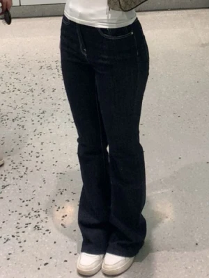 Mörkblå bootcut jeans - Snygga mörkblå bootcut jeans med klassisk femficksdesign och kontrastsömmar. Jeansen har hög midja och utsvängda ben, perfekta för en trendig och avslappnad look. Passar grymt till sneakers eller boots.