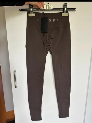 Bruna leggings från RELODE - Snygga bruna leggings från relode med hög midja och scrunch-detalj bak. Tillverkade i ett stretchigt material som sitter tight och bekvämt. Perfekta för en trendig och avslappnad stil.