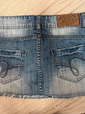 Lågmidjad jeanskjol  - Säljer den här jättesnygga jeanskjolen då den är för stor för mig. Storleken har suddats ut på lappen men skulle säga den passar som en S. Midjemått rakt över är 40 cm och längden är 28 cm. Pris går att diskutera. Perfekt nu till sommaren!!