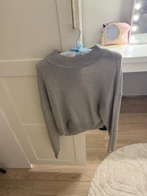 Grå stickad tröja med rund hals - En enkel och stilren grå stickad tröja med rund halsringning och långa ärmar. Tröjan har en mjuk och slätstickad yta, perfekt för lager på lager. Passar till det mesta och är lätt att matcha med andra plagg.