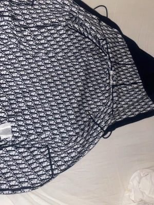 Mörkblå hoodie - Snygg mörkblå hoodie från HM med ikoniskt Oblique-mönster på insidan av huvan. Utsidan är enfärgad och har en klassisk huva med dragsko. Tillverkad i mjukt material som känns skönt mot huden. Perfekt för dig som vill ha en exklusiv och trendig look.