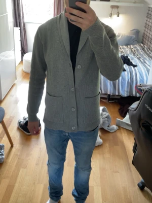Cardigan - Säljer en grå cardigan från Pier One i fint skick. Enkel och stilren modell som passar till det mesta, både vardag och lite mer uppklätt.