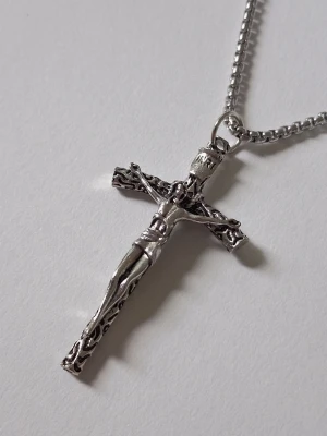 Silverfärgat korshalsband - Snyggt halsband med ett detaljerat kors i silverfärgad metall. Hänget har en Jesusfigur och dekorerade kanter som ger ett klassiskt och stilrent intryck. Kedjan är tunn och matchar hängets färg perfekt. Perfekt accessoar för dig som gillar religiösa smycken. Materialet rostfritt stål. 