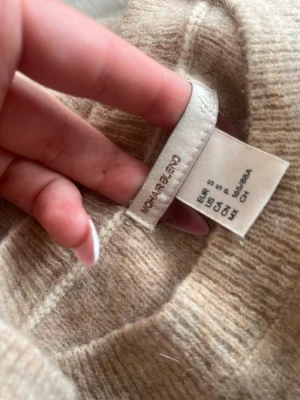 Beige stickad tröja från MONKI - Mysig beige stickad tröja från MONKI i storlek S. Tröjan har en enkel, rak passform med rund halsringning och långa ärmar. Materialet är mjukt och ger en avslappnad look, perfekt för lager på lager under kyliga dagar.