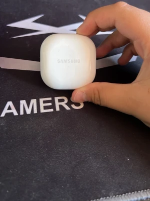 Samsung trådlösa in-ear hörlurar - Säljer ett par stilrena trådlösa in-ear hörlurar från Samsung. Hörlurarna är svarta och kommer i ett vitt, kompakt laddningsetui med rundade former. Perfekta för musik, poddar och samtal på språng. Laddningsetui medföljer.