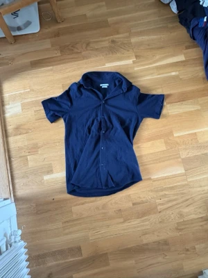Mörkblå kortärmad skjorta från Zara - Snygg mörkblå skjorta från Zara i regular fit. Skjortan har korta ärmar, klassisk krage och knäppning framtill. Perfekt för en stilren look och enkel att matcha med jeans eller shorts.