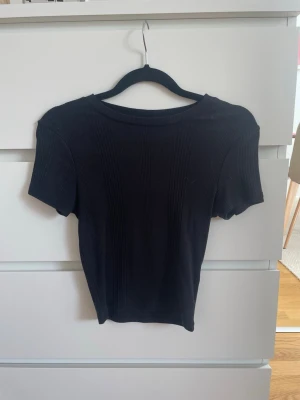 Svart t-shirt - Svart T-shirt i tajtare passform från Gina Tricot i strl XS. Använd men fortfarande i fint skick