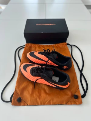 Nike Hypervenom Phantom RGN SE FG -  Nike Hypervenom Phantom RGN SE FG | Strl 42 | HELT NYA ⚽  Säljer ett par Nike Hypervenom Phantom RGN SE FG i svart/orange. Helt nya och aldrig använda.  ✅ Storlek: 42   ✅ Skick skor: Nya / oanvända   ✅ FG (gräs)   ✅ Skopåse medföljer (använd men i bra skick, se bilder)  🔥 En eftertraktad och svår modell att få tag på.  📦 Skickas snabbt.   📸 Se bilder för detaljer och skick.