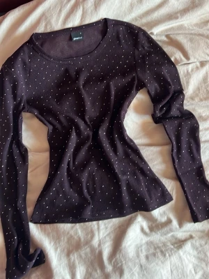 Mörklila/röd topp med glittriga prickar - Snygg mörklila/röd långärmad topp från Gina Tricot med glittriga prickar över hela tyget. Tunn och lätt mesh-känsla, perfekt för att lyfta din outfit. Figurnära passform och rund halsringning. Endast använd en gång 