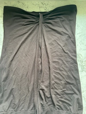 Brun axelbandslös topp - En enkel brun axelbandslös topp i mjuk bomull. Toppen har en rak passform och rynkad detalj upptill som ger en snygg effekt. Perfekt för dig som gillar minimalistisk stil och vill ha något bekvämt och stilrent. Banden kan man knyta runt halsen!