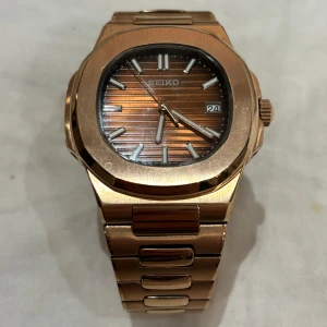 Seiko Mod Nautlius (Seikonaut) - Hej! Säljer en fin Seikonaut i rosé guld med chokladbrun urtavla. Klockan är i gott skick men såklart har den använts några gånger därav extremt lågt pris. NH35 Urverk, safir glas och öppen baksida. 