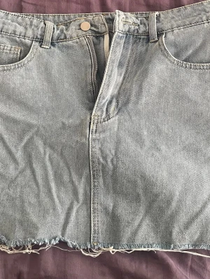 Kort jeanskjol  - Säljer en ljusblå jeanskjol som passar perfekt under sommaren. Har aldrig använts