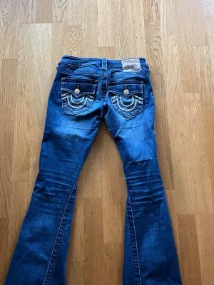 True religion jeans - Säljer ett par blå bootcuts jeans från true religion. Jeansen har låg midja och är jätte snygga plus är true religion jeans väldigt sköna. Har lite slitning mellan benen mer syns inte när du har på dig och så har sytt ihop ett hål på knät. De kostar 1700kr i vanliga fall, om du har frågor så svarar jag gärna 💕