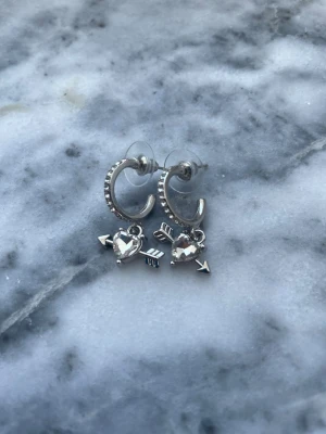 Silvriga örhängen med 💘och diamanter  - Säljer ett par silverfärgade örhängen HELT nya och oanvända. De har en liten diamant sten i form av hjärta syns ej så bra på bild men örhängena är mycket glansiga ✨✨