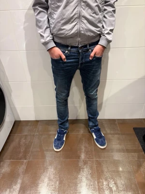 Dondup george - Snygga mörkblå slim fit jeans med klassisk femficksdesign och diskreta slitningar. Jeansen har smal passform och normal midja, perfekta till sneakers och vardagsstil. Materialet är denim med lätt stretch för extra komfort.