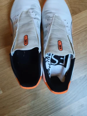 Vita Puma King match inomhus skor  - Säljer ett par vita Puma King fotbollsskor med röd detaljer och svart insida. Skorna har en slimmad design och greppvänlig sula i röd gummi, perfekt för snabba vändningar på planen. Ovandelen är i syntetmaterial med elastisk plös för bra passform.(Kommer med ett gratis par grepstrumpor på köpet)
