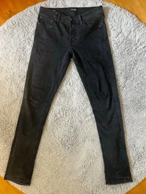 Svarta Jack and Jones jeans - Säljer dessa nygga svarta Jack and Jones jeans med klassisk femficksdesign. Dom är i väldigt fint skick! Inga hål eller något liknande. Är i storlek W28 L32 och modell är Slim Glenn. Skriv bara vid funderingar!