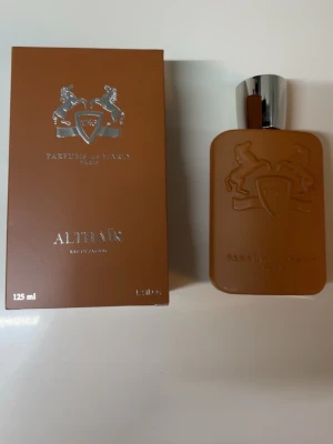 Parfums de Marly Althaïr EdP 125ml - Exklusiv parfym från Parfums de Marly, Althaïr Eau de Parfum i en snygg brun flaska med silverdetaljer och reliefmönster av hästar. Flaskan rymmer 125 ml och har en modern, stilren design. Perfekt för dig som gillar lyxiga dofter och elegant förpackning. Med kvitto!