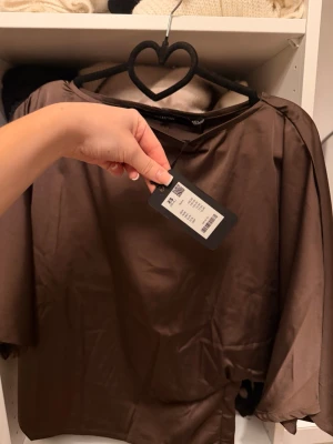 SATIN TOPP - Snygg brun satin topp som går in i midjan med volangärmar. Den är oanvänd från lager 157 och är supersnygg för många tillfällen!!😍😍💋💌Säljer byxorna som är i setet i profilen 