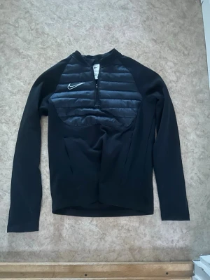 Nike Träningströja  - Snygg svart långärmad Nike träningströja med halv dragkedja. Perfekt för träning . Nike-logga på bröstet och mjukt, värmande material som håller dig varm. Storlek 147-158, men jag hade när jag hade storlek XS så jag rekommenderar att man är cirka 150-170.
