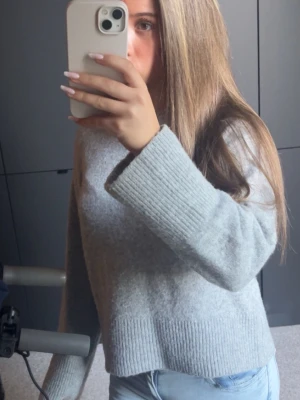 Grå stickad tröja från Gina tricot  - Mysig grå stickad tröja med bred ribbad mudd vid ärmslut och nederkant. Tröjan har en avslappnad passform och rund halsringning. Perfekt för lager på lager och enkel att matcha med olika stilar. ! OSÄKER PÅ STORLEK MEN TROR XS!