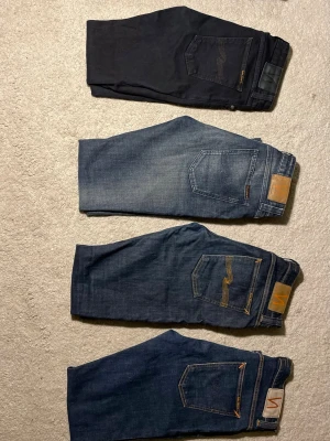 Fem  par jeans från Nudie Jeans - Säljer fem par snygga jeans från Nudie Jeans i olika tvättar: ett par svarta och tre par blå jeans med olika slitningar och detaljer på bakfickorna. Klassisk femficksmodell och raka ben. Perfekta för dig som gillar stilrena och tidlösa jeans.