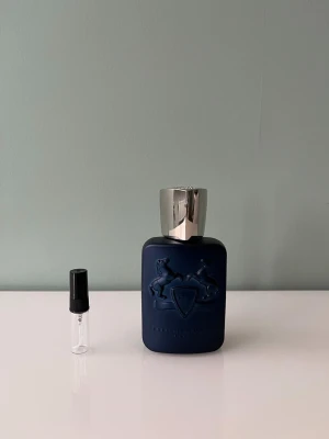 1 ml sample av Parfums de Marley Layton - Ett sample på 1 ml av Parfums de Marly Layton. Det är en kryddig vinterparfym av Parfums de Marly. Den börjar starkt och kryddigt, efter ett tag blir den mer söt med vanilj. Våra samples är helt nya och är gjorda av glas. Det är fritt fram att skriva till oss om ni har frågor.