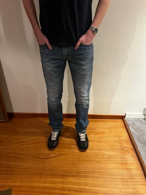 Blå raka jeans i klassisk modell - Säljer ett par blå jeans med rak passform och normal midja. Jeansen har en klassisk femficksdesign och är tillverkade i denim med lätt tvättad look. Perfekta till sneakers och t-shirt för en avslappnad stil.
