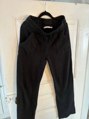 Svarta mjukisbyxor från Lager 157 - Säljer ett par svarta mjukisbyxor från Lager 157 med bred resår i midjan och dragsko. Byxorna har två stora fickor framtill och är gjorda i mjukt bomullsliknande material. Perfekta för chill dagar eller när du vill vara bekväm. Passar S/M