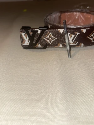 Brun bälte med v buckle - Helt nytt och snyggt bälte, 110 cm långt. Bra kvalitet och aldrig använt. Har du frågor? Dm gärna 