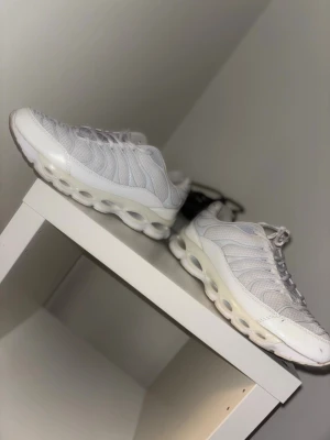 Vita sneakers med unik sula - Säljer ett par vita skor med mesh och syntetmaterial. Skorna har en vågig design på ovandelen och en tjock, futuristisk sula med hål för extra komfort och stil. Perfekta för dig som vill ha något som sticker ut och är riktigt fresh.