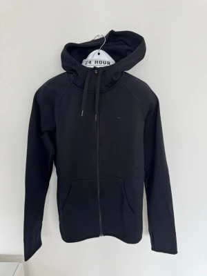 Nike - Träningshoodie - Snygg svart hoodie från Nike med dragkedja framtill och två stora fickor. 