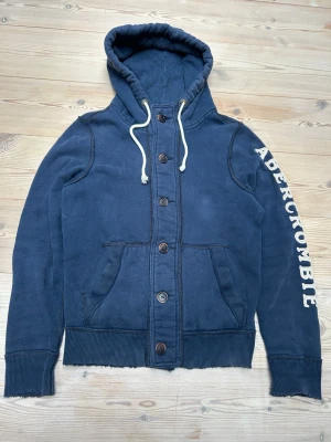 Abercrombie & Fitch hoodie  - Säljer denna eftertraktade Abercrombie & Fitch hoodie med knappar, den är i fint skick. Den är i storlek M men passar också S!  Hör av er vid minsta lilla fråga! Pris ej hugget i sten!  Kolla min profil för mer liknande plagg 😊