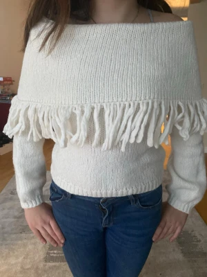 Lindex vit off shoulder stickad tröja - Säljer en vit stickad tröja med off shoulder-modell och bred krage med långa fransar runtom. Har bara används en gång förut!Perfekt för vintern eller när det är kallt!🫰🏼💕 