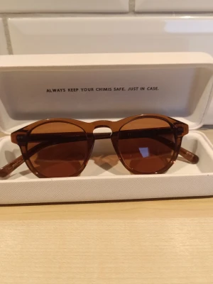 Bruna solglasögon från Chimi - Snygga solglasögon från Chimi i en rundad form med bruna bågar och matchande bruna glas. Klassisk design som ger en cool vibe och passar perfekt till soliga dagar. Kommer i originalfodral.