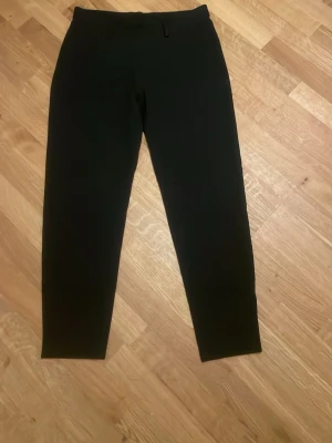 Svarta leggings med hög midja - Säljer ett par svarta leggings med hög midja och smal passform. De är stretchiga och sitter tight längs benen, perfekta till en avslappnad eller trendig look. Materialet känns mjukt och följsamt. Inga synliga detaljer eller loggor.