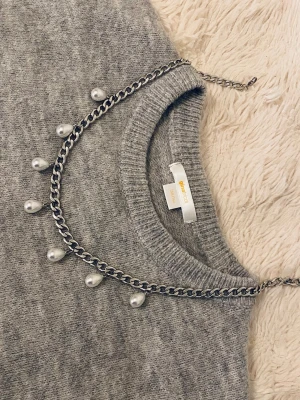 Kedjehalsband med droppformade pärlor - Snyggt halsband i silverfärgad metallkedja med droppformade vita pärlor som hänger längs kedjan. Halsbandet har en modern och edgy vibe och passar perfekt för att lyfta vilken outfit som helst.