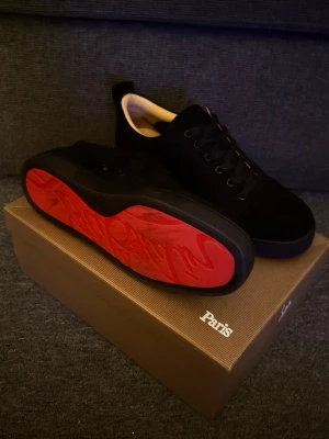 Svarta Christian Louboutin skor - Snygga svarta skor från Christian Louboutin, med den klassiska röda sulan, skon är i mocka, därför fungerar den som finskor men den funkar även att ha i vardagen