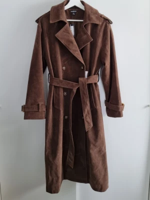 Vintage trench coat S/M kappa mocka suede chokladbrun - Oversized mörkbrun kappa från Boohoo i stl S (passar som M). Otroligt fin färg. Helt ny med lapparna kvar, nypris 1768 kr     #klassisk #trench #coat #suede #fauxleather #chocolate #mocka #imitation #trendig #vintage #scandinavian #unik #witchy #boohoo #alternative #rare #treasure #capsule #retro #60s #70s #oldmoney #unique #high #quality #elegant #statement #piece #premium #luxury #stilren #chic #casual #winter #spring #autumn #scandi
