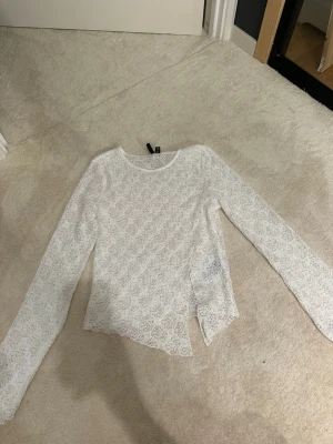 Vit spetsblus med lång ärm - Säljer en vit långärmad blus i spets med rund halsringning. Blusen har ett genombrutet spetsmönster och asymmetrisk nederkant som ger en cool touch. Perfekt att styla lager på lager eller med ett linne under. Skriv för frågor osv🥰