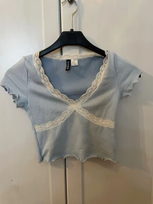 Ljusblå ribbad topp med spets - Supersöt ljusblå ribbad topp perfekt till sommaren. Toppen är croppad och super söt! Varsamt använd men har varit en av mina favorit toppar! Pris kan diskuteras. OBS! Köparen står för frakt