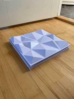 Vita 3D väggpaneler i plast - Säljer ett gäng vita 3D väggpaneler med geometriskt mönster. Panelerna är fyrkantiga och gjorda i plast, perfekta för att skapa en modern och cool effekt på väggen. Passar bra till inredningsprojekt där du vill ha en unik look.