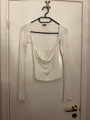 Vit långärmad topp med drapering - Trendig vit långärmad topp från ginatricot, Figurnära passform och mjukt stretchigt material som känns skönt mot huden.