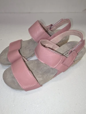 Helt Nya !.Soft Comfort Rosa sandaler I skinn stl 37-23.7cm P1P - Snygga sandaler i ljusrosa med breda remmar och öppen tå. Ovandelen är i mjukt skinn och innersulan är beige och är i mocka. Sandalerna har justerbar hälrem och en låg platåsula i naturfärgat material (Levereras utan låda i en postorderpåse)  Soft Comfort är ett svensktägt skovarumärke med över 15 års erfarenhet, som fokuserar på att kombinera ergonomi, funktionalitet och skandinavisk design. Varumärket riktar sig främst till den medvetna kvinnan