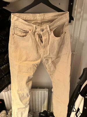 Levi's 501  raka jeans - Säljer ett par klassiska Levi's 501 jeans i vit denim. De har rak passform, knappgylf och fem fickor. Perfekta för dig som gillar en tidlös och clean look. Levi's-lappen bak och den röda lilla taggen på fickan ger den där ikoniska känslan.