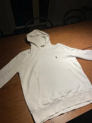 Vit hoodie från Polo Ralph Lauren - Snygg vit hoodie från Polo Ralph Lauren med klassisk huva och känguruficka framtill. Liten broderad logga på bröstet i mörkblått. Kan gå ner i pris vid snabb affär!